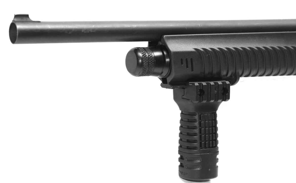 Close-up of a black tactical shotgun or rifle stock with a vertical foregrip and a mounted optic, shown against a plain white background.