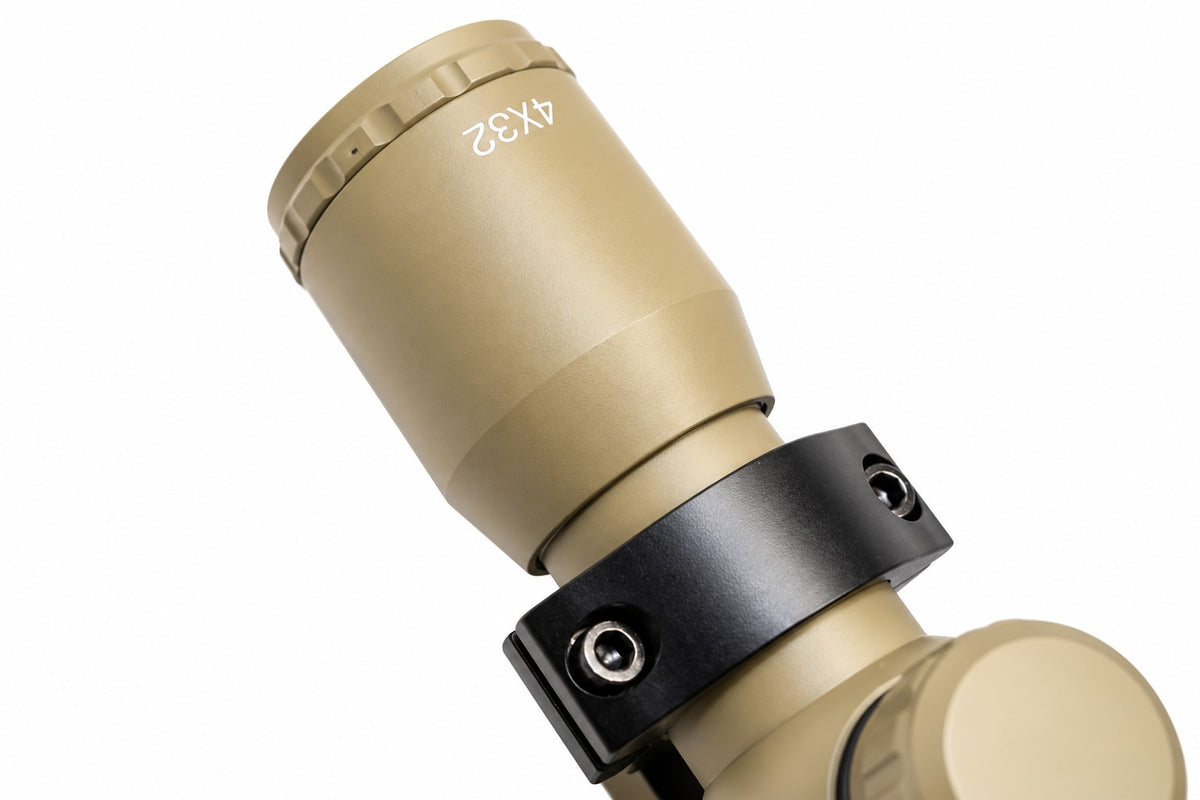TRINITY 4x32 Mil-Dot scope in tan with blue multi-coated objective lens, aluminum housing, adjustment turrets, and black dovetail mounting rings on a white background.